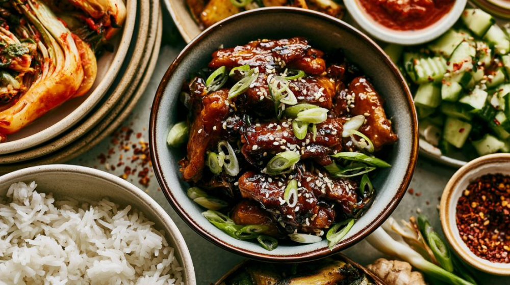 Koreaanse maaltijd met sticky kip, rijst, kimchi, groenten en pittige saus met sesam en bosui.